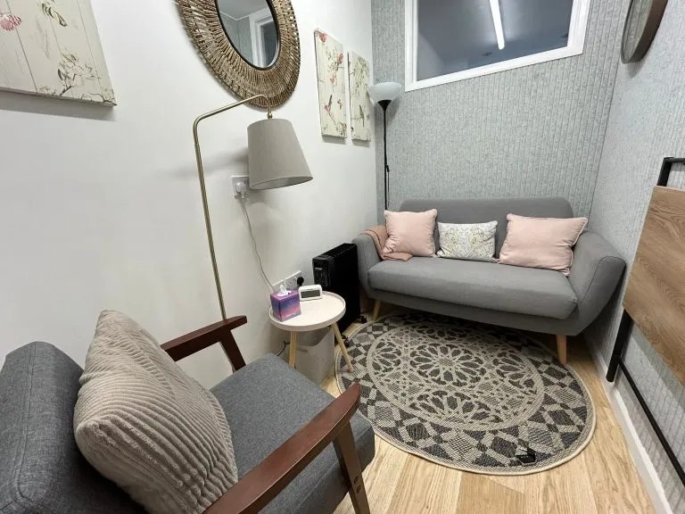 The quiet therapy room in East Dulwich, with a sofa, an armchair and a soft lamp